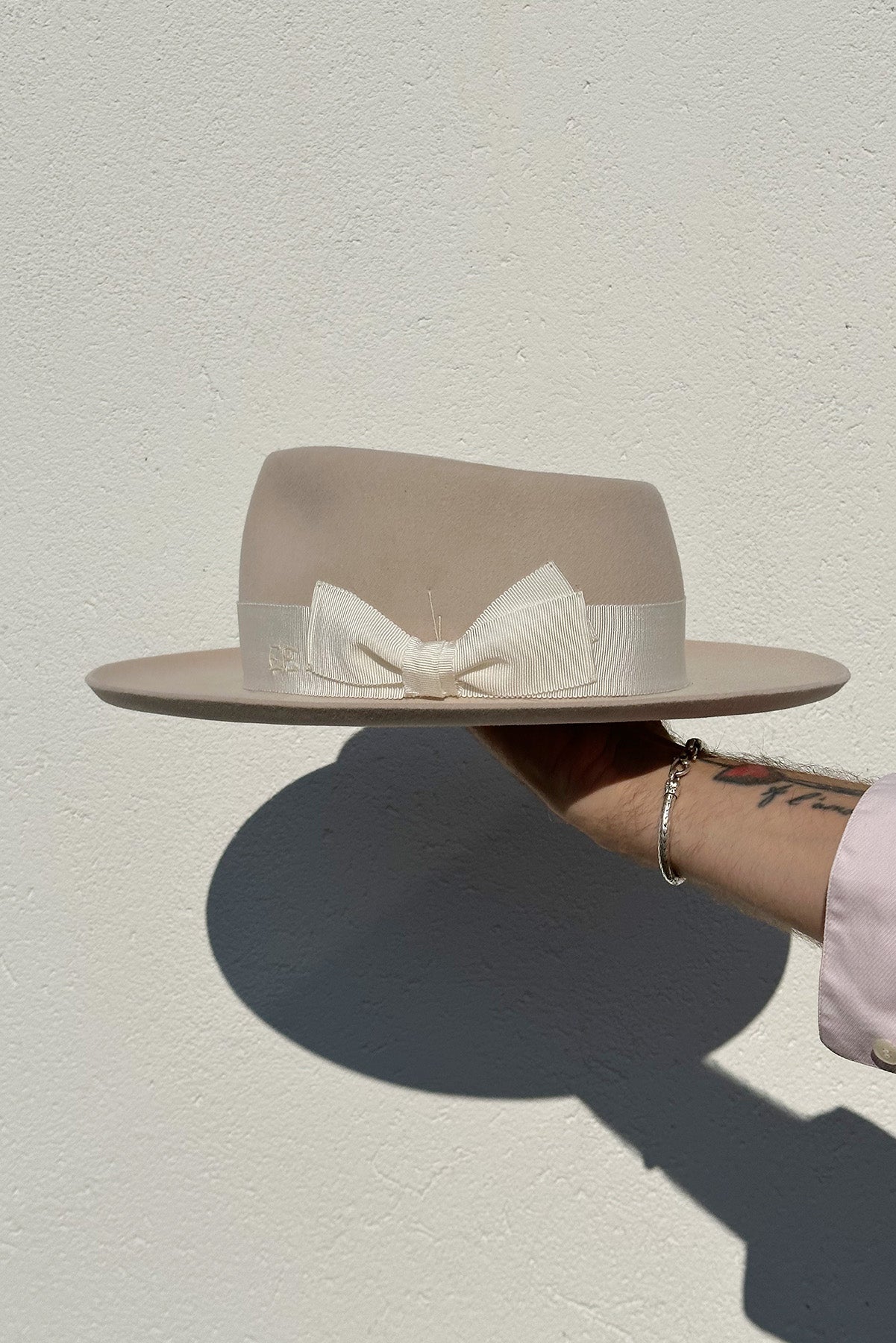 beige fedora hat with large white bow