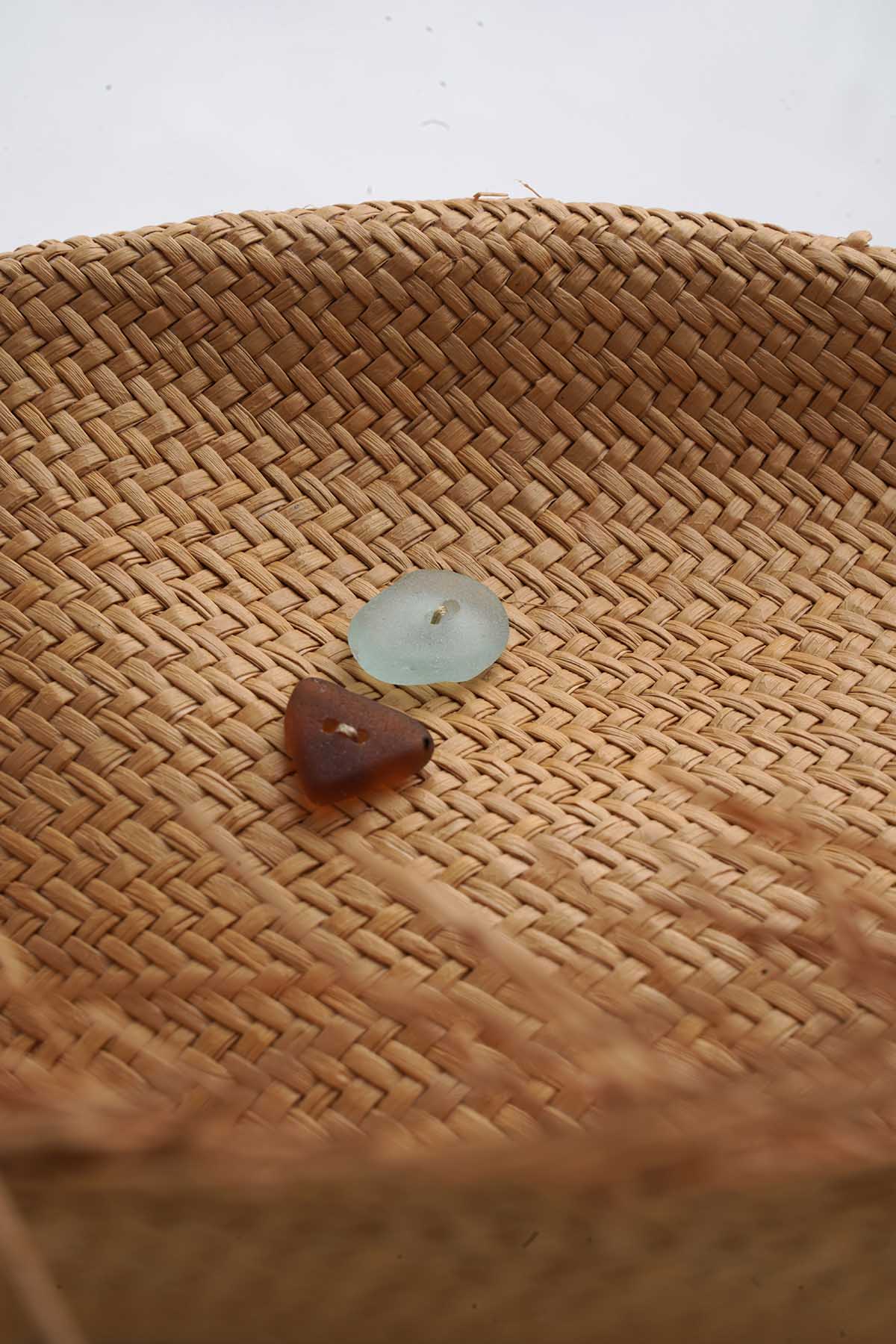 Close-up of two small glass beads on a woven straw hat