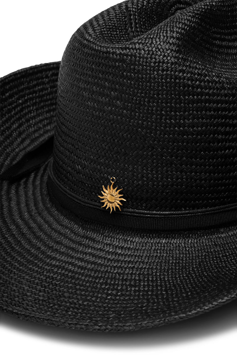 A close up of a black straw cowboy hat with a s gold plated sun attached to the back.