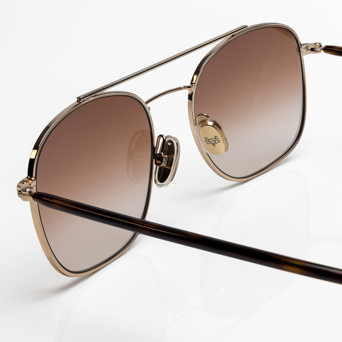 A pair of oversized square aviator-style sunglasses with a gold-tone metal frame, brown gradient lenses, and dark tortoiseshell temple arms, shown on a clean white background.